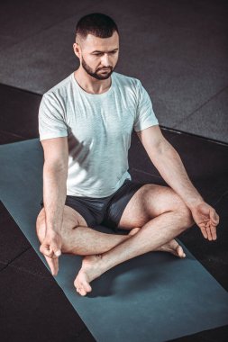 Erkek yogası pozu. Delikanlılar içeride siyah minder üzerinde yoga yapıyor. Spor salonunda siyah bir geçmişi olan yoga yapan bir adam. Nilüfer çiçekleri gibi meditasyon yapan genç adamlar. Eğitim kavramı.