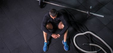 Eğitimden sonra dinleniyorum. Spor salonundaki paspasın üzerinde oturan sakallı genç adamın bakışları. Yüksek resulotion resmi.