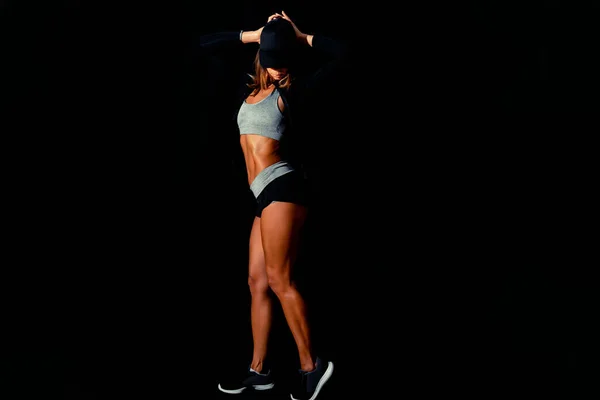 一个漂亮的女人把背靠在黑色的背景上 性感的健身模特儿在黑漆漆的工作室里训练后汗流浃背 — 图库照片
