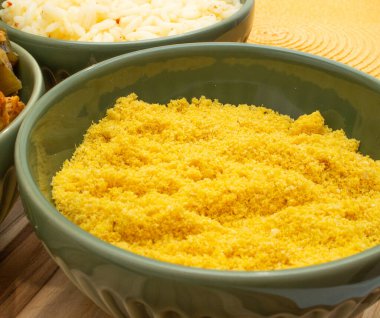 Pirinç dolu kaselerde Brezilya yemeği ve ahşap arka planda un.