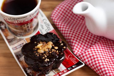 Bir fincan kahve ve ahşap masanın altında siyah arka planda bir çikolata şekeri.