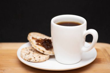 a cup of coffe beside a  rice vegan cookies with jelly on the top