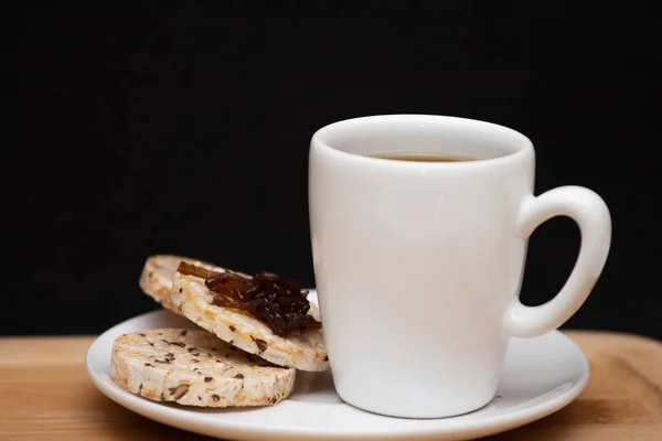 a cup of coffe beside a  rice vegan cookies with jelly on the top