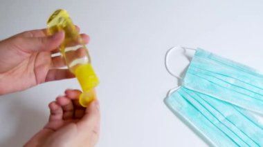 Evde izolasyonda el dezenfektanı kullanmak. Koronavirüs salgını sırasında virüs ve bakterilerin yayılmasını önlemek için çıplak ellere jel dezenfeksiyonu uygulamak. Beyaz arkaplanda mavi maskeler.