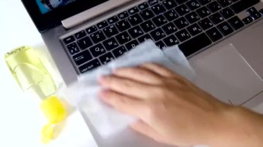 Hastalık ve koronavirüsün yayılmasını önlemek için klavyeyi ıslak mendille temizliyorum. Evde izolasyon sırasında bakterileri, mikropları ve virüsü öldürmek için teknoloji yüzeyi yıkamak. Sarı jel dezenfektan şişesi.