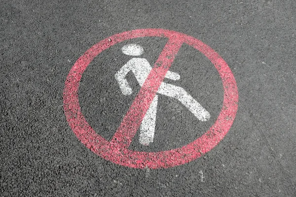 White road markup signal on concrete asphalt. Transportation restrictions on the way. No pedestrians allowed, no walking, driving and riding bicycles only. Red painted crossed sign with person inside.