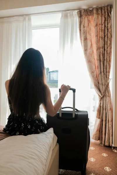 Sad young woman with luggage ready to leave the hotel room. Last day of vacation. Time to go back home. Short trip during isolation, restricted travel. Leaving finished weekend getaway spa retreat.