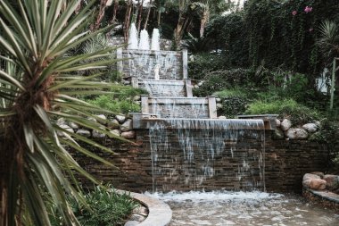 Belek, Türkiye - Ekim 2020: Her şeyi kapsayan otel bölgesinde heykeli olan güzel şelale. Huzurlu bir çevrede lüks bir tatil. Antalya 'da romantik bir tatil köyünde su akıyor..