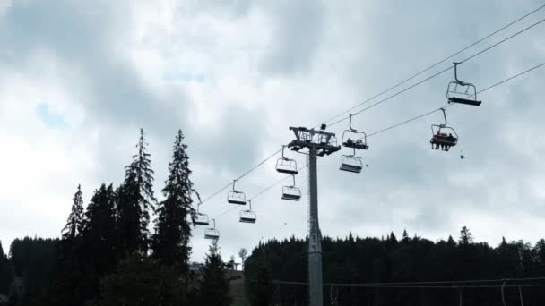 夏のスキーリフトで地面からの眺め 曇り灰色の曇りの空 暗い機嫌の良い天気 観光客が森や山にロープを上下に飛んで電気自動車 週末屋外 — ストック動画