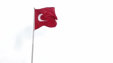 Red Turkish flag in a windy weather. White sky in background. Popular tourist destination for sea vacation in all inclusive hotel. Patriotic symbol of Turkey. Flag on a pole trembling because of wind.