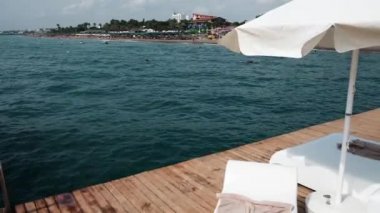 Luxury vacation at sea. Special vip place with sunbeds and umbrella on the dock, overview of the beach and deep ocean water. Resting at beautiful tropical destination during sunny summer day at a pier