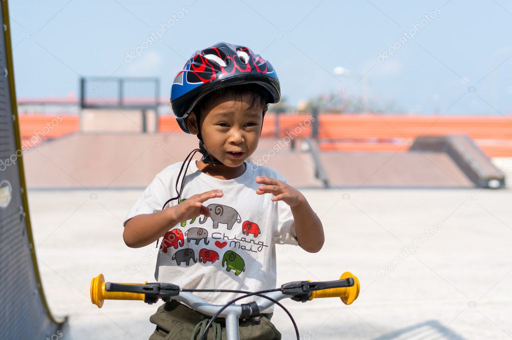 Little boy wearing helmets ridding bike .