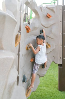 Happy young handsome boy ( kid ) playing on climbing sets in a park clipart