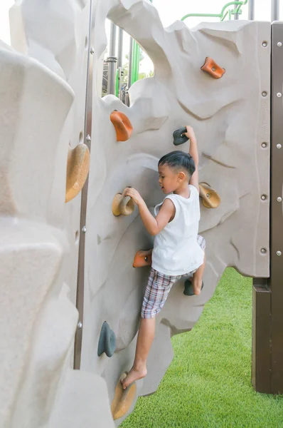 Rapaz bonito (criança) feliz jogando em conjuntos de escalada em um parque — Fotografia de Stock