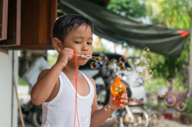 Asyalı çocuk çocuk kabarcıkları ile sabun köpüğü ile oynamak