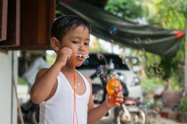 Asyalı çocuk çocuk kabarcıkları ile sabun köpüğü ile oynamak