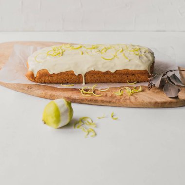 Tahta servis tabağında beyaz çikolata soslu ve limon aromalı nefis ev yapımı kek. Kolay geleneksel İngiliz tatlı yemeği. Ev yapımı tatlı. Aşçılık sanatı ya da yemek blogu.   