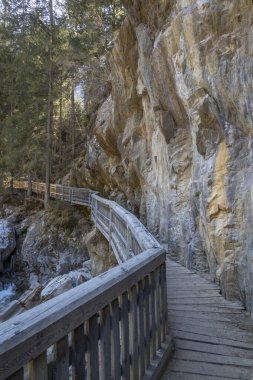 Tahta yol ve Alplerdeki dağ nehri üzerinde köprü.