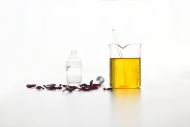 Beyaz arka planda serumun hazırlanmasında bitki özleri ve sebze yağlarıyla test tüpü.