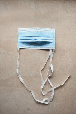 Pembe beton desenli arka planda mavi cerrahi maske portre biçiminde