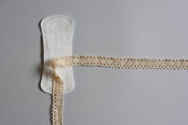 Gri arka planda, kumaş döngüsü ve konsepti olan kadınlar için özel adet pedi.