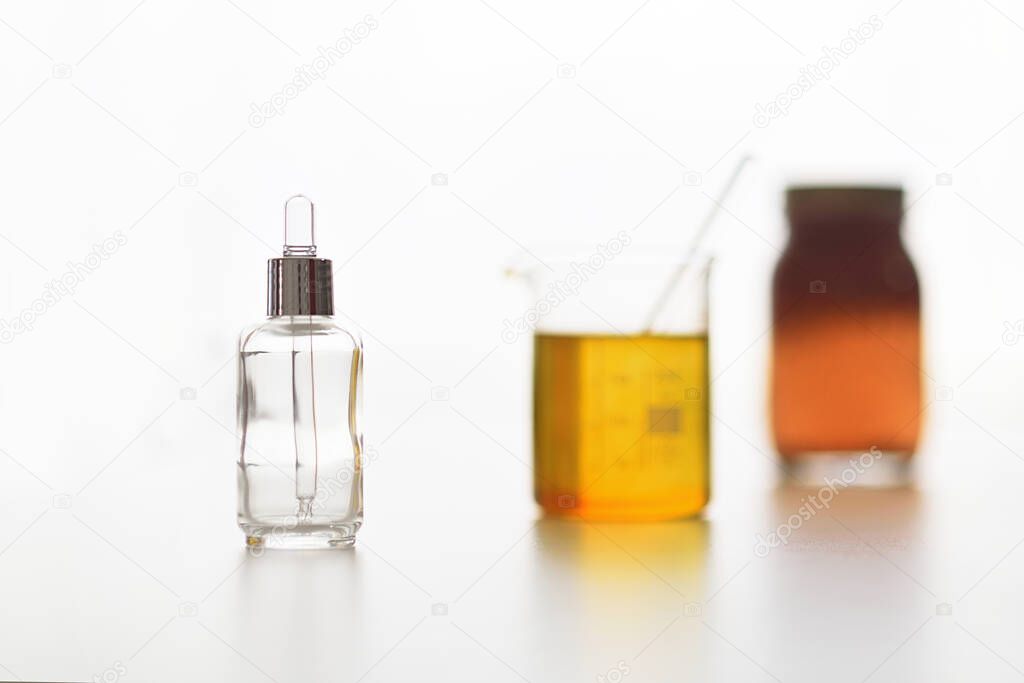 Process of elaboration of natural elixir with vegetable oils and empty bottle on white background
