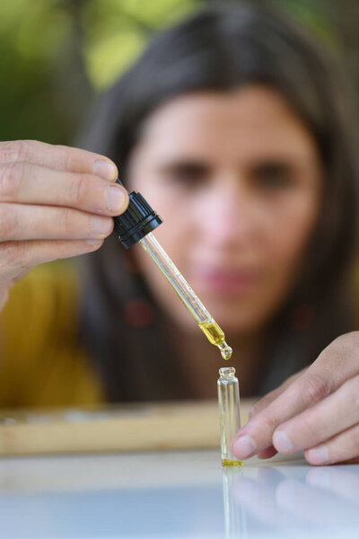 Woman with dropper bottling a sample of essential oil