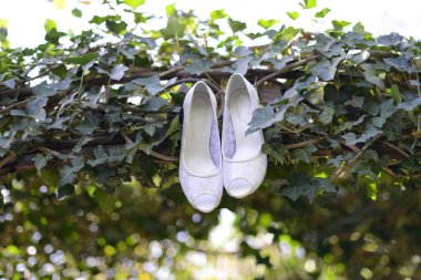 Bahçeye asılmış beyaz gelinlik ayakkabıları.