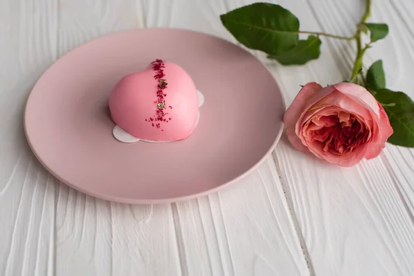 ピンク色の皿の上に鏡釉をかけたハート型のピンクケーキ 白い木の背景にピンクと白のバラの花束 バレンタインデーおめでとう お誕生日おめでとう 女性の日 ストック写真