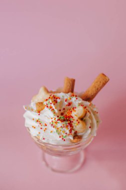 Pembe arka planda bir bardakta kremalı tatlı..