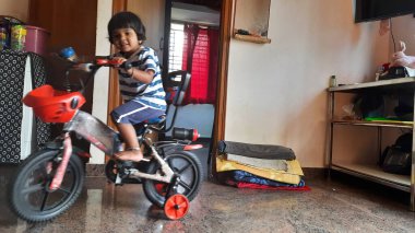 Hintli bir kızın evde küçük bir bisiklete binmesi ya da öğrenmesi.