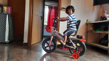 Hintli bir kızın evde küçük bir bisiklete binmesi ya da öğrenmesi.
