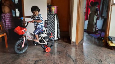 Hintli bir kızın evde küçük bir bisiklete binmesi ya da öğrenmesi.