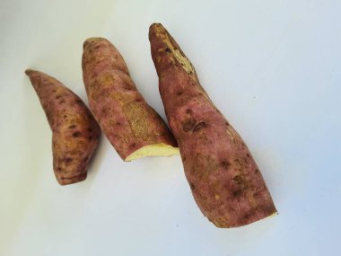 Dışı pembe ve içi sarı renkli tatlı patates yığını beyaz arkaplanda izole edilmiş.