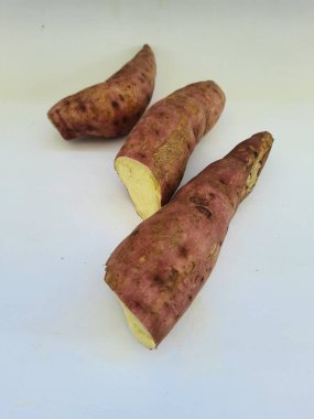 Dışı pembe ve içi sarı renkli tatlı patates yığını beyaz arkaplanda izole edilmiş.