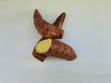 Dışı pembe ve içi sarı renkli tatlı patates yığını beyaz arkaplanda izole edilmiş.