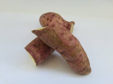 Dışı pembe ve içi sarı renkli tatlı patates yığını beyaz arkaplanda izole edilmiş.