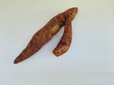 Dışı pembe ve içi sarı renkli tatlı patates yığını beyaz arkaplanda izole edilmiş.