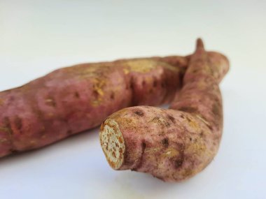 Dışı pembe ve içi sarı renkli tatlı patates yığını beyaz arkaplanda izole edilmiş.