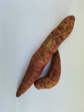 Dışı pembe ve içi sarı renkli tatlı patates yığını beyaz arkaplanda izole edilmiş.