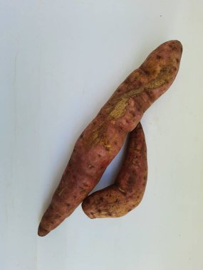 Dışı pembe ve içi sarı renkli tatlı patates yığını beyaz arkaplanda izole edilmiş.