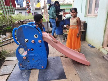 Bangalore, Karnataka, India-Dec 06-2020: Mobil Plastik slaytlarda oynayan Hintli çocuklar grubu, evin önünde dağcılar