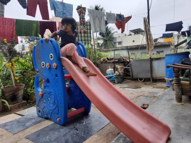 Bangalore, Karnataka, India-Dec 06-2020: Mobil Plastik slaytlarda oynayan Hintli çocuklar grubu, evin önünde dağcılar