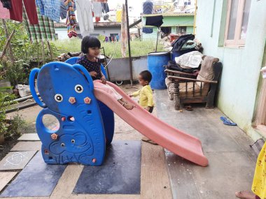 Bangalore, Karnataka, India-Dec 06-2020: Mobil Plastik slaytlarda oynayan Hintli çocuklar grubu, evin önünde dağcılar