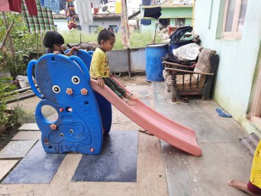 Bangalore, Karnataka, India-Dec 06-2020: Mobil Plastik slaytlarda oynayan Hintli çocuklar grubu, evin önünde dağcılar