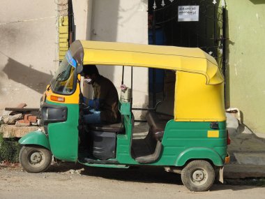 Bangalore 'un yol kenarına yeşil ve sarı renkli çekçek park yeri, sürücü içeride oturuyor..