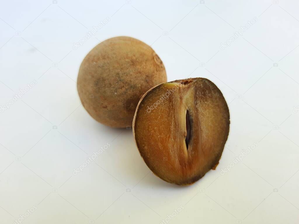 Closeup of beautiful full and half sliced Brown color Chickoo or Sapota Fruit isolated on white background