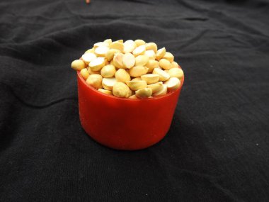 Kızarmış Gram Yığını kırmızı renkli plastik bardakta ve siyah arkaplana saçılmış geleneksel kum kasesinde yakın plan.