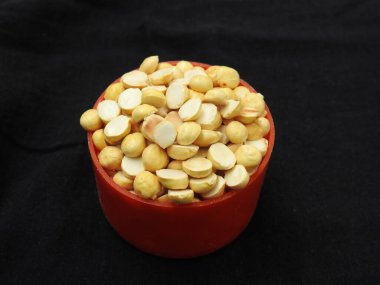 Kızarmış Gram Yığını kırmızı renkli plastik bardakta ve siyah arkaplana saçılmış geleneksel kum kasesinde yakın plan.