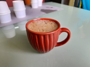 Beyaz arka planda izole edilmiş kahve dolu kırmızı renkli seramik kahve fincanı.